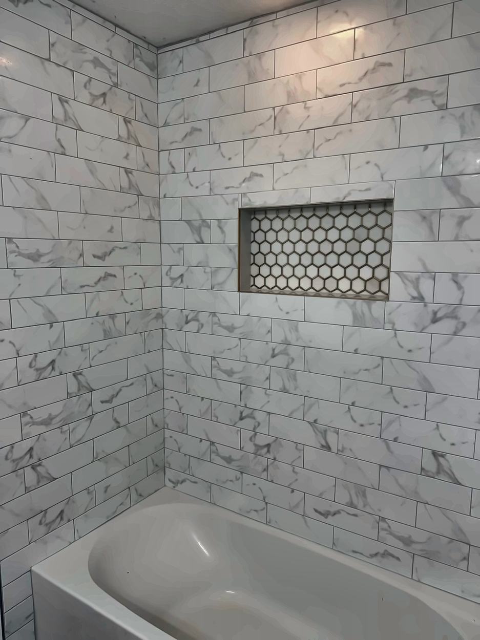 Subway-tiled tub surround with a recessed niche in gold-grouted hexagon mosaic
