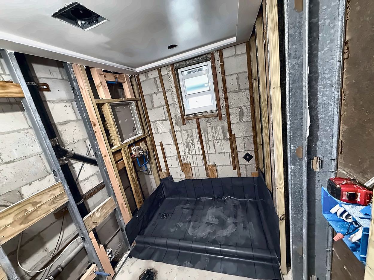 Rough-in stage with new PEX supply, a set valve and the black shower pan liner folded into the corners
