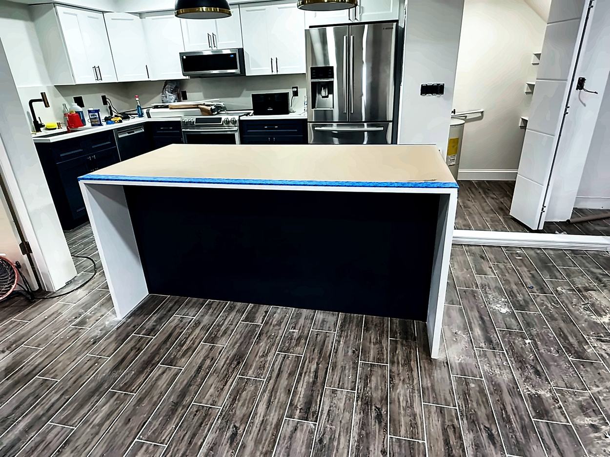Kitchen island built out in navy with a raw taped top awaiting its quartz slab