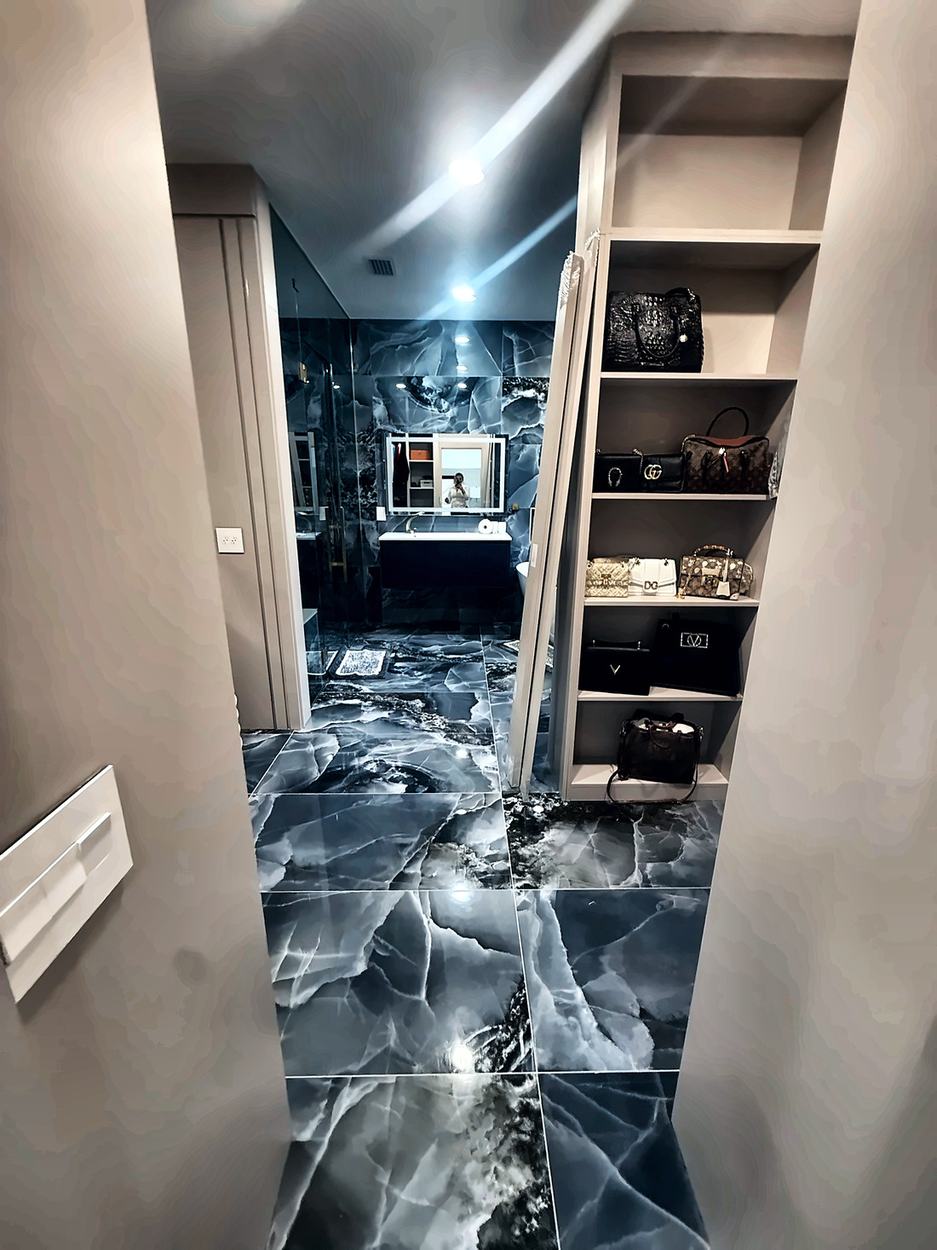 Dressing corridor with built-in panelled shelving opening onto the onyx primary bathroom